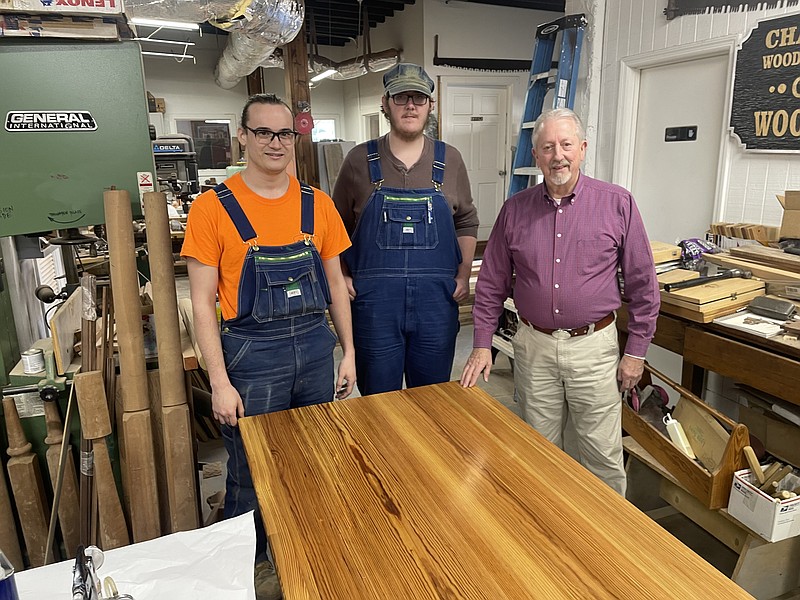 Staff photo by Mark Kennedy / From left, Michael Clark, Brandon Lebanon and Bill Carney pose Wednesday with a heart-pine table destined for Poe's Tavern, a historical replica building in Soddy-Daisy. The table was handmade by students Clark and Lebanon at the Chattanooga Woodworking Academy on Market Street.