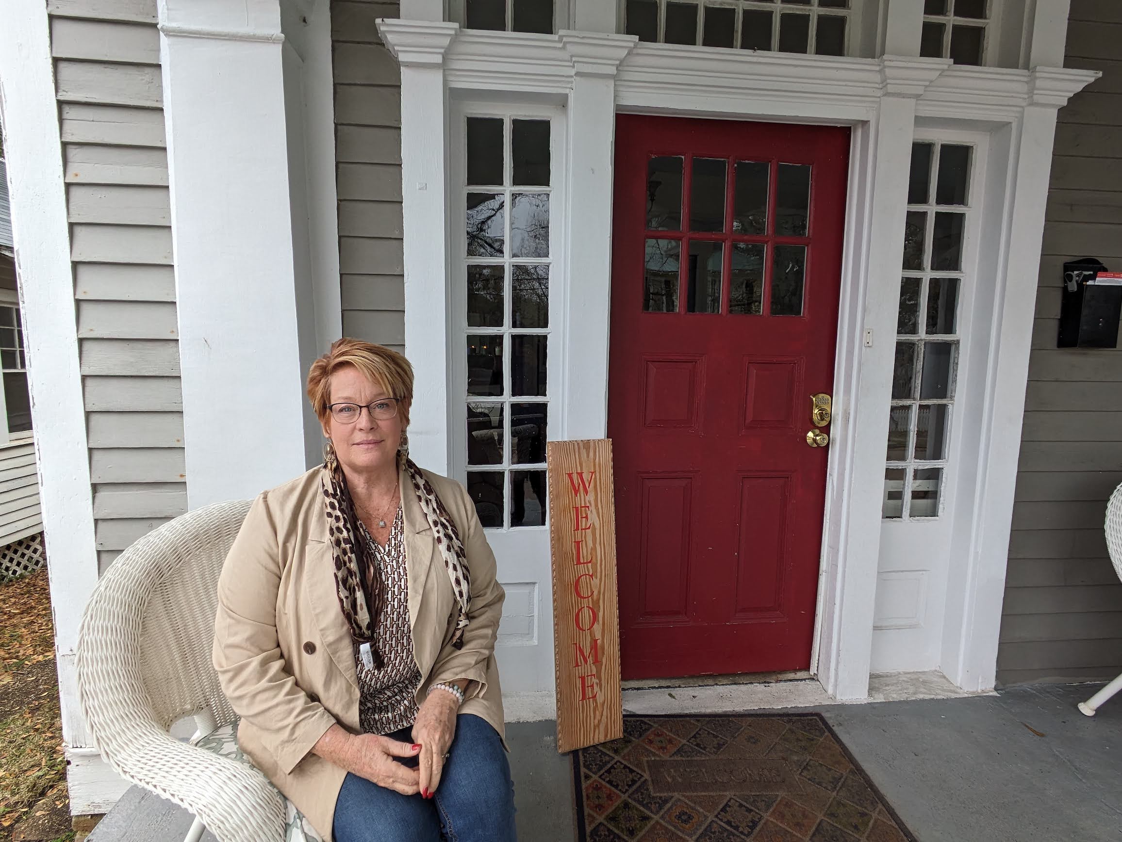 Lisa Teggart, executive director of the Door to Serenity sober living homes, sits outside the women's home she runs in Mobile, Ala. The house has nine beds. Teggart says she must regularly turn people away until she can afford to expand. (Aneri Pattani/KFF Health News)
