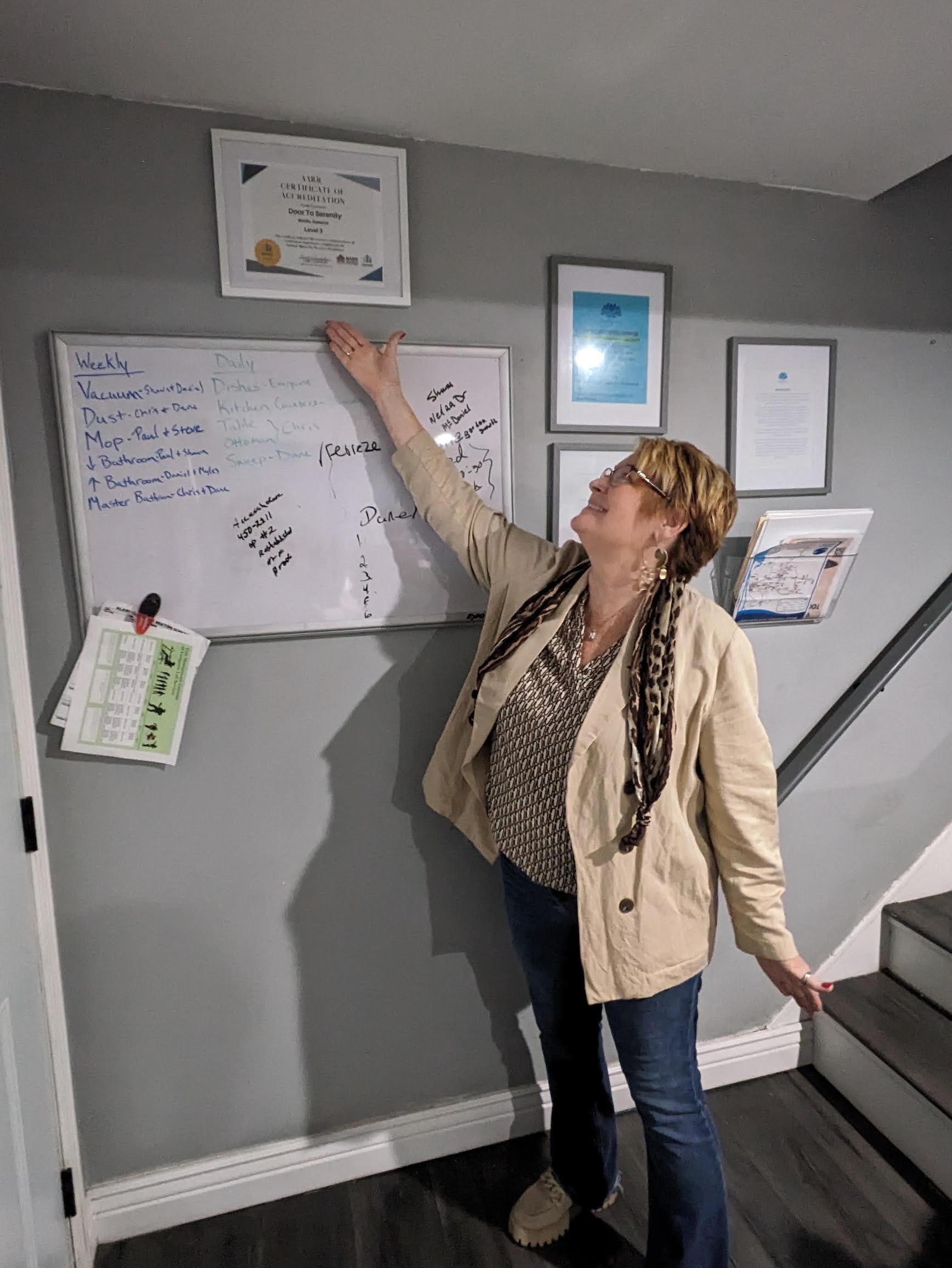 Lisa Teggart, executive director of the Door to Serenity sober living homes in Mobile, Ala., proudly points to her certification from the Alabama Alliance for Recovery Residences. The certification indicates her homes meet national criteria for being safe spaces for people in recovery to live in a drug-free environment. (Aneri Pattani/KFF Health News)