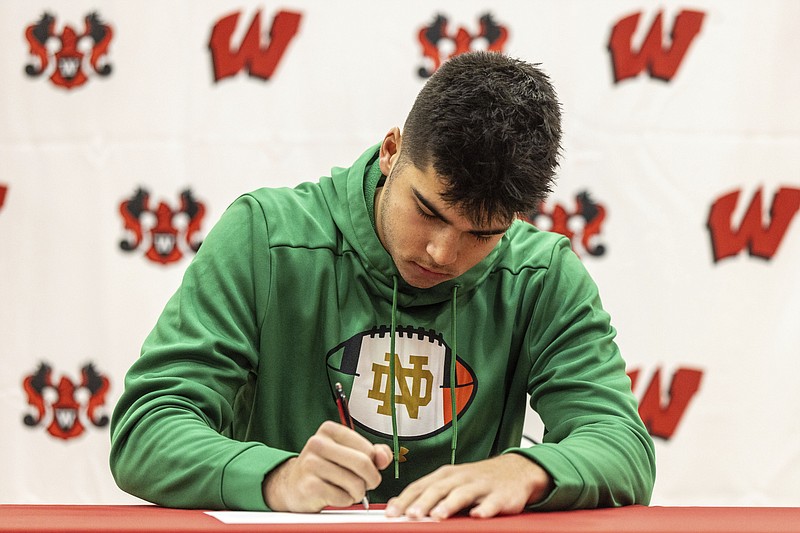 Omaha World-Herald leader photo by Chris Machian via AP / Omaha (Neb.) Westside linebacker Teddy Rezac signs a letter of intent to play for Notre Dame on Dec. 20. Major college football's early signing period, which was instituted in 2017, is moving from late December to the week before conference championship games starting this fall.