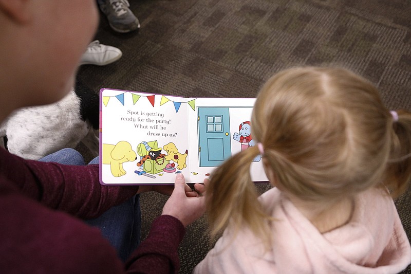 Staff File Photo / Leslie Van Duinen reads "Find Spot at the Library" with her 1-year-old daughter Avery during Fetch a Book, a program put on by the Chattanooga Public Library for kids to learn to read alongside a dog from the McKamey Animal Center, on Tuesday, Feb. 18, 2020.