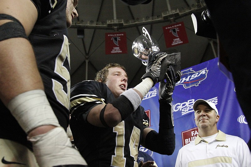 Staff file photo / Calhoun High School football coach Hal Lamb looks on as Clay Johnson is handed the Class AA State Championship trophy l at the Georgia Dome in Atlanta in 2011.