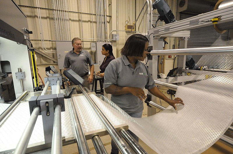 Staff File Photo / Machine operator Jackie Albey, right, works at her station making air filter material at eSpin Technologies.