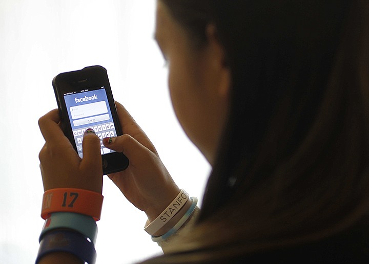 AP File Photo/Paul Sakuma / In this June 4, 2012, photo, an unidentified 11-year-old girl logs into Facebook on her iPhone at her home in Palo Alto, California.