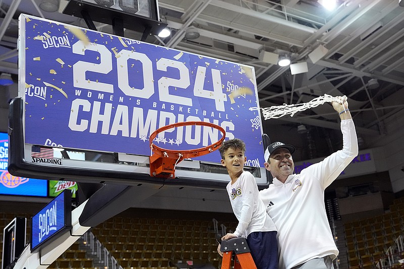 AP photo by Kathy Kmonicek / With his son Kai by his side, UTC women's basketball coach Shawn Poppie waves the cut net in the air to celebrate his team's 69-60 win over UNC Greensboro in the SoCon tournament final on March 10 in Asheville, N.C.