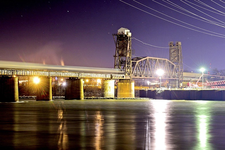 Staff File Photo By Robin Rudd / Lit by the construction lights from the ongoing build of a new lock at Chickamauga Dam, a Norfolk Southern freight train crosses the TenBridge over the Tennessee River on Jan. 11, 2022.