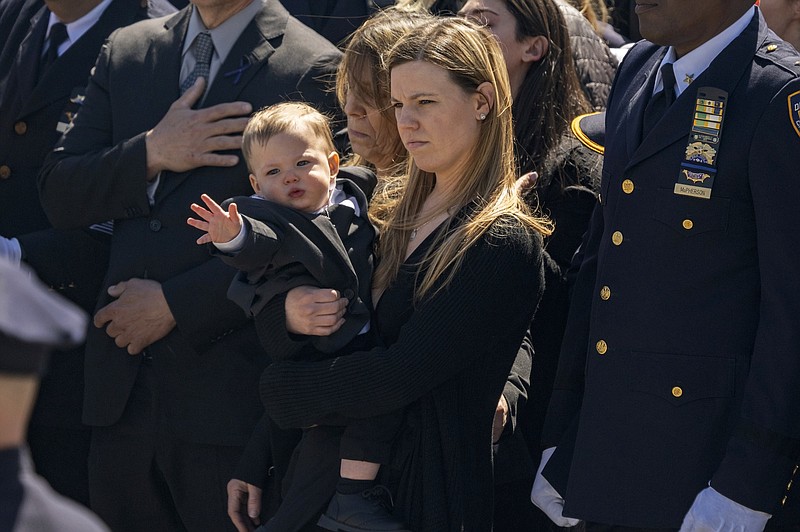 Photo/Jeenah Moon/The Associated Press / Stephanie Diller and her son watch the casket during a funeral service for her husband, New York City Police Department Officer Jonathan Diller, at Saint Rose of Lima R.C Church in Massapequa Park, N.Y., on Saturday, March 30, 2024. Diller was shot and killed during a traffic stop.