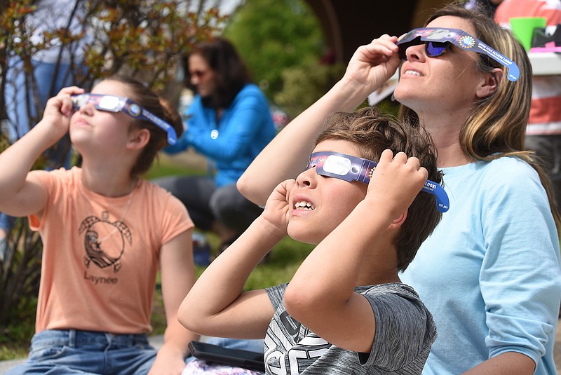 Staff photo by Matt Hamilton / Soddy-Daisy resident Elizabeth Massey, right, watches the eclipse with her children Henry, 9, front, and Laynee, 12, at the Northgate branch of the Chattanooga Public Library on Monday.