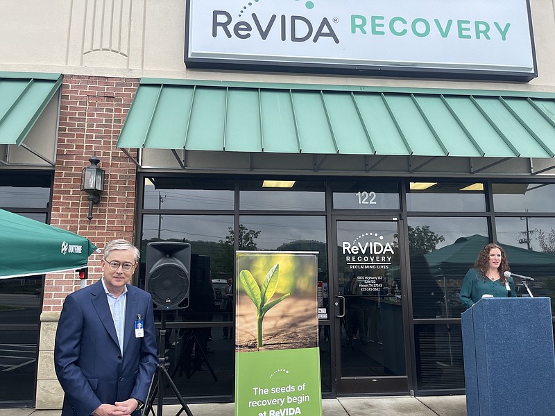 Staff Photo by Dave Flessner / Jennifer Cooke, program director for the Revida Recovery Center in Chattanooga, talks at the podium Wednesday while company CEO Lee Dilworth, left, listens. Revida acquired the former Renu in Hixson last December and celebrated Revida's expansion into the Chattanooga market during a Chattanooga Area Chamber of Commerce ribbon-cutting Wednesday.