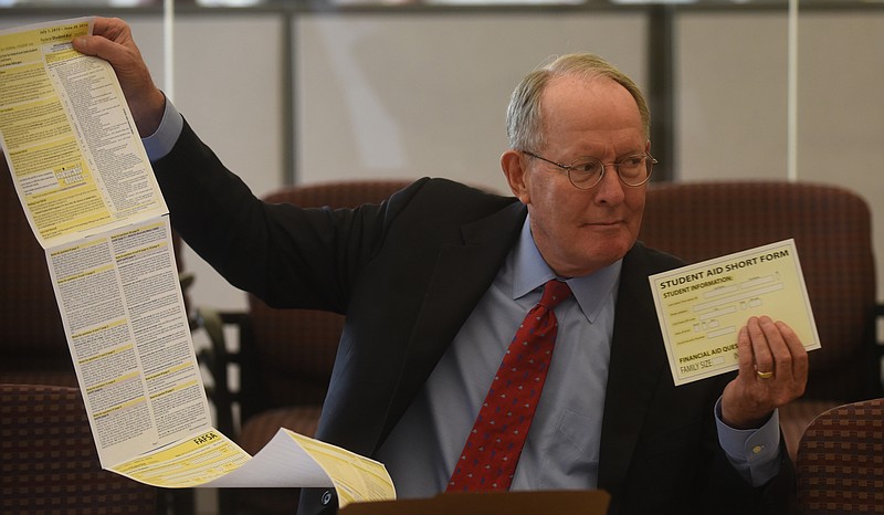 Staff Photo / Then-Sen. Lamar Alexander, R-Tenn., holds up a federal student aid application and a post-card sized version he wanted to implement during a visit to the Chattanooga Times Free Press in 2015. In a new interview, the retired senator criticized the rollout of a new federal student aid application.