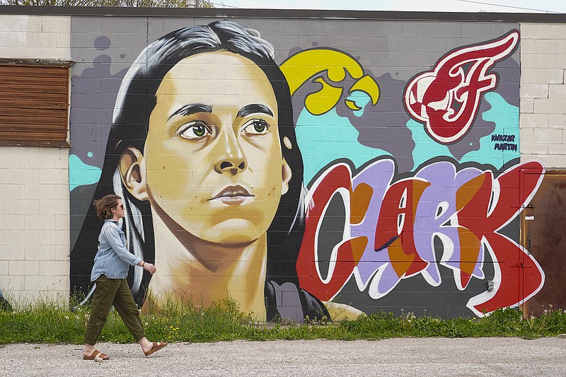 AP photo by Michael Conroy / A pedestrian walks past a mural by Kwazar Martin featuring Indiana Fever guard Caitlin Clark in Indianapolis on April 16. The Fever selected Clark, a former Iowa Hawkeyes star and the all-time leading scorer in NCAA Division I basketball history, with the No. 1 overall pick in the WNBA draft the night before.