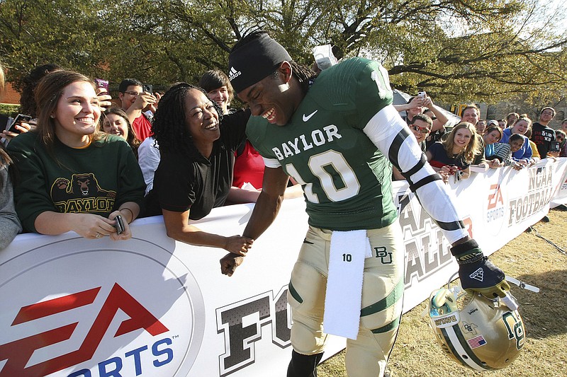 Waco Tribune-Herald photo by Jerry Larson via AP / Former Baylor University quarterback Robert Griffin III, the 2011 Heisman Trophy winner, is greeted by Holly Johnson on campus on Feb. 27, 2012, in Waco, Texas, where he posed for photos for EA Sports' "NCAA Football 13" video game to be released that July.