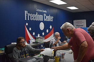 Staff Photo by Andrew Wilkins / On election day in 2022, Ringgold resident James Qualls signs in to vote at the Freedom Center in Ringgold, while poll workers Taylor Lankford (left) and Jim Skeen assist voters.