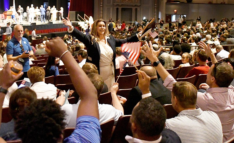 Staff Photo by Robin Rudd / Mercy Rodriguez-Kealey, center, of the McCallie School, acknowledges the applause of family, friends and well-wishers after becoming a U.S. citizen Wednesday. Almost 400 people became United States citizens at a naturalization ceremony for the U.S. District Court Eastern District of Tennessee at Chattanooga at the Soldiers and Sailors Memorial Auditorium on Wednesday