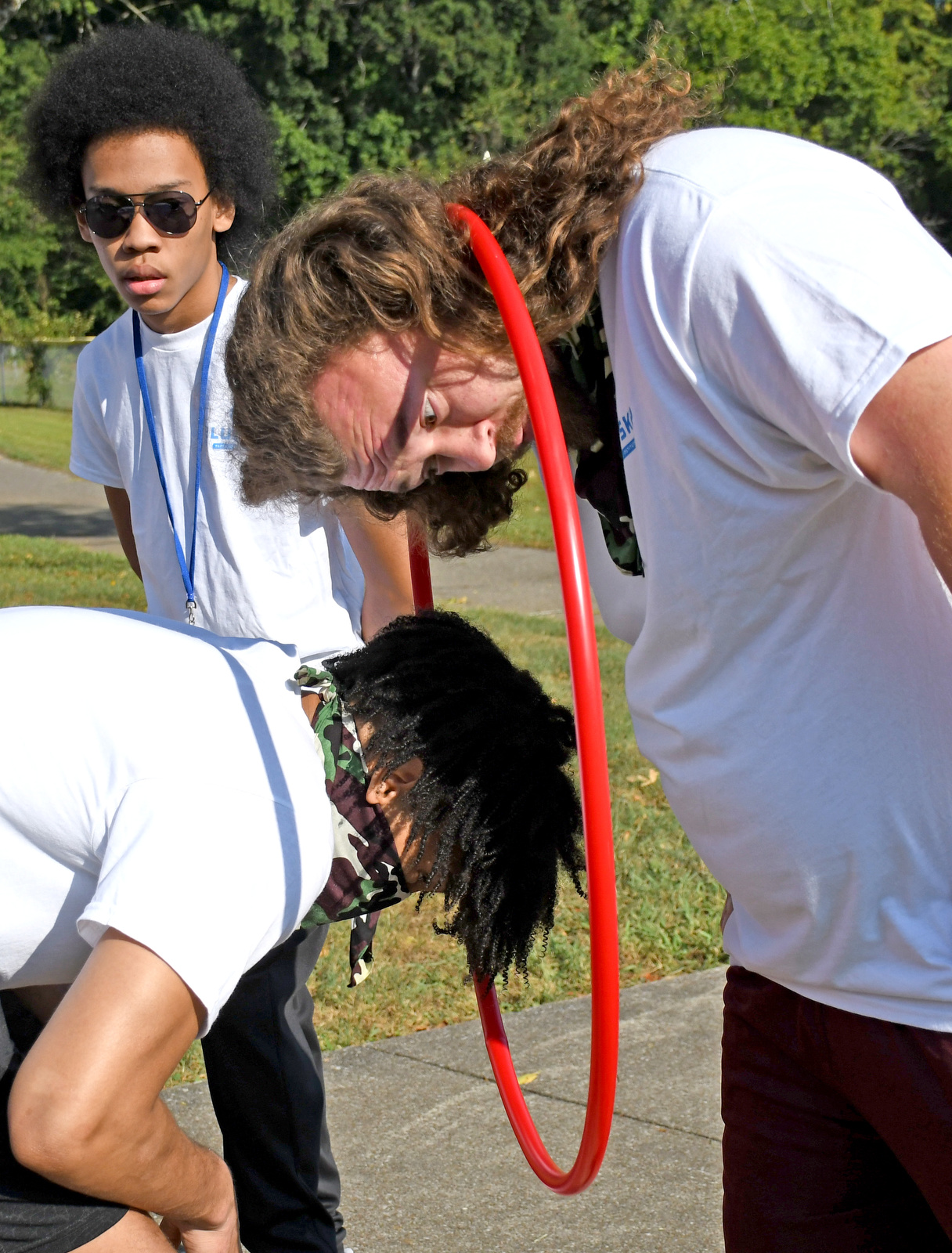 Staff Photo by Robin Rudd / The camouflage team's Caleb Greenhaw, top, and Dennis Tate pass the hula hoop only using their necks during a color wars team building exercise at the St. Elmo Recreation Center on Aug. 20, 2024. The BlueSky Institute at BlueCross BlueShield Tennessee is a 27-month tech workforce development program that allows students to obtain a degree, learning from university professionals, and get a job with the company upon graduation.