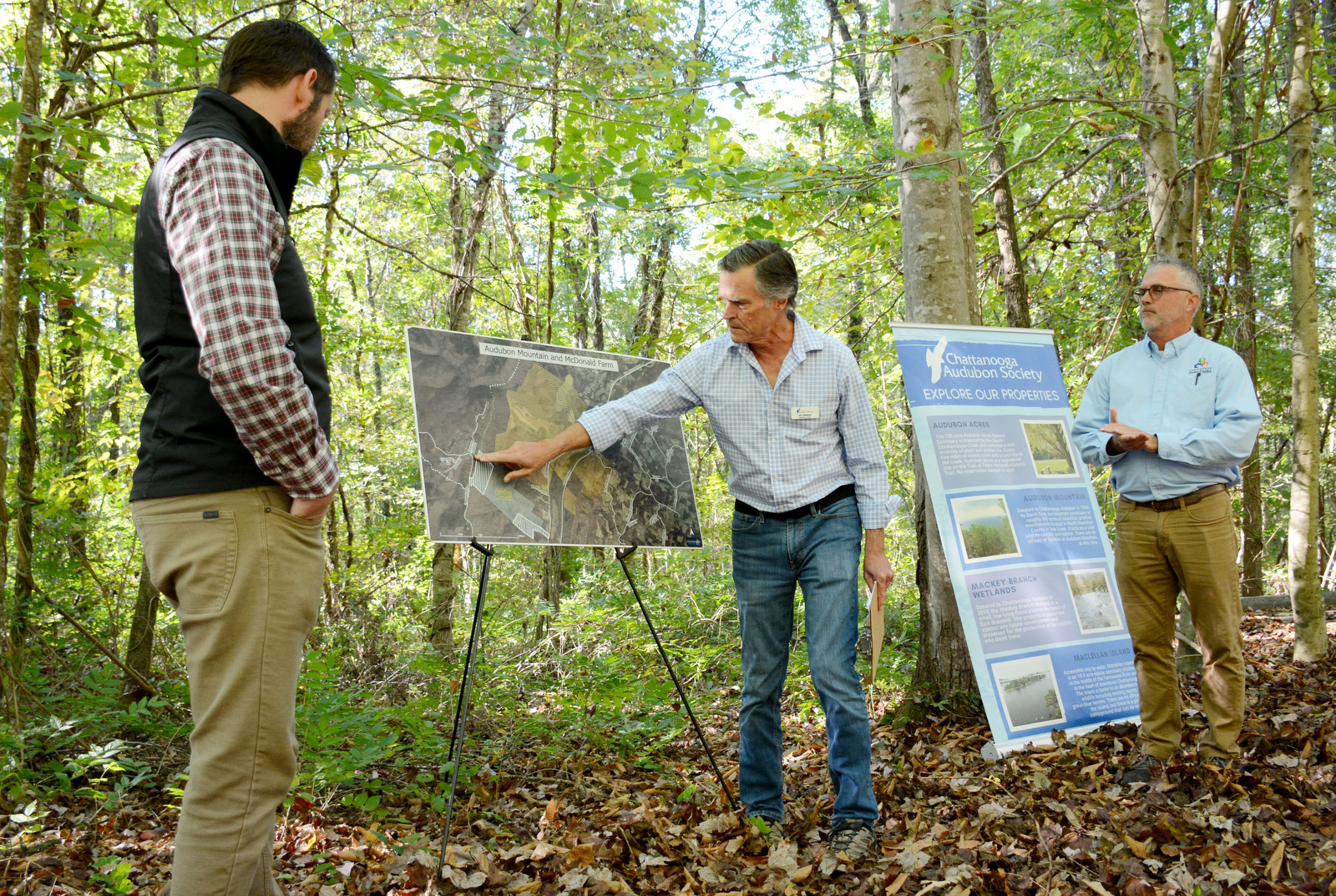 Staff Photo by Robin Rudd / Jim Stewart, Chattanooga Audubon Society executive director, points Oct. 8, 2024, to a map showing the land involved in a swap between his organization and Tennessee State Parks. Listening are Matt Fola, director of parks for Hamilton County, left, and Bill Avant, real property manager for the state of Tennessee, at a Cumberland Trail access point on Leggett Road in Sale Creek.