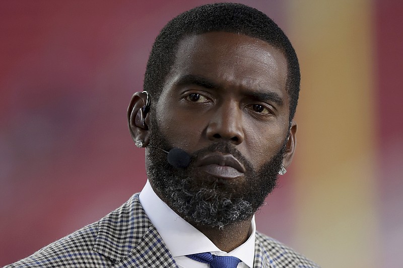 AP photo by Scot Tucker / NFL broadcaster and Pro Football Hall of Fame receiver Randy Moss sits on the sideline before a game between the San Francisco 49ers and the visiting Los Angeles Rams in November 2021.