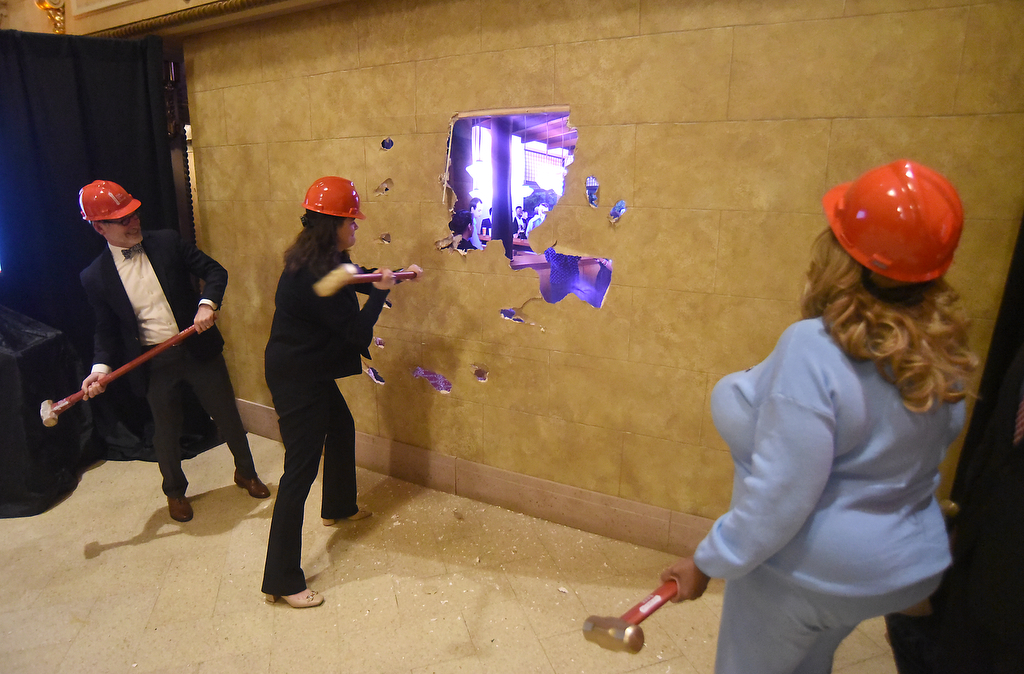 Staff photo by Matt Hamilton / Officials knock through a wall Dec. 17, 2024, during a ceremony to mark the official start of the Tivoli Theatre renovation.