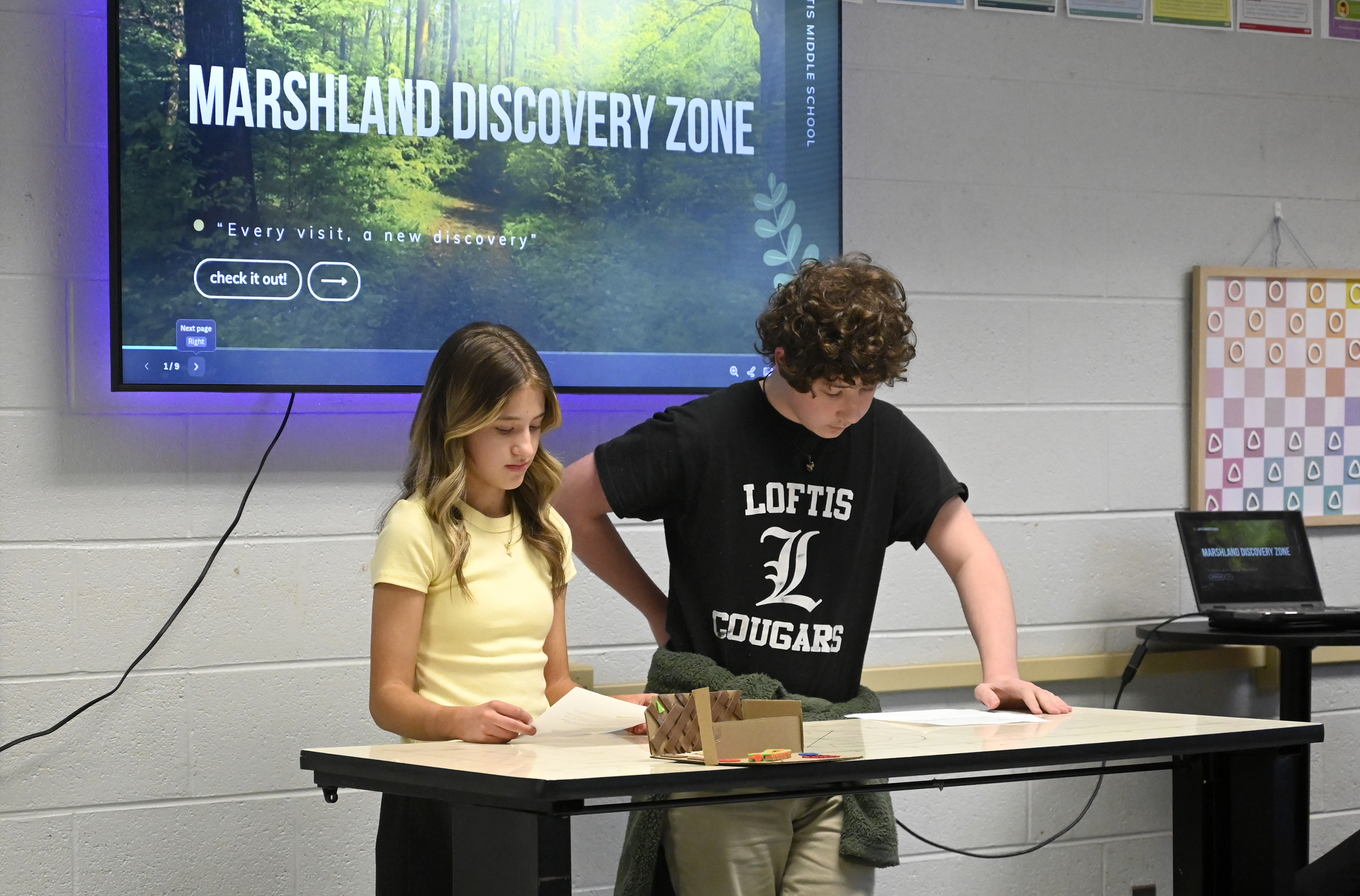 Staff photo by Abby White / Students listen March 12, 2025, as Makenleigh Young, left, and Skylar Rollins give their presentation on the Marshland Discovery Zone. Eighth grade students at Loftis Middle School are working to create an outdoor learning area with wildlife habitats, observation spaces and hands-on learning environments as part of their project-based learning efforts.