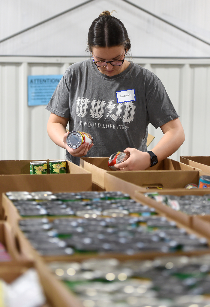 Staff photo by Matt Hamilton/ Volunteer Savannah Boyle packs food into a box for distribution at the Chattanooga Area Food Bank on Friday, April 4, 2025.