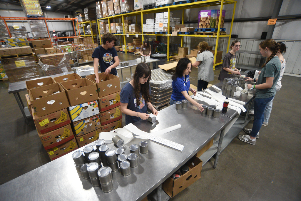 Staff photo by Matt Hamilton/ Volunteers place labels on cans of cream corn at the Chattanooga Area Food Bank on Friday, April 4, 2025.