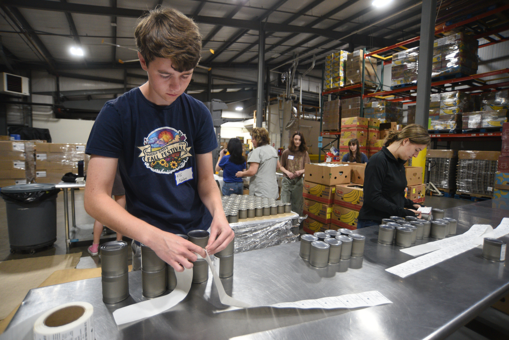 Staff photo by Matt Hamilton/ Volunteers Eli Noles, 16, left, and Zeda Spencer place labels on cans of cream corn at the Chattanooga Area Food Bank on Friday, April 4, 2025.