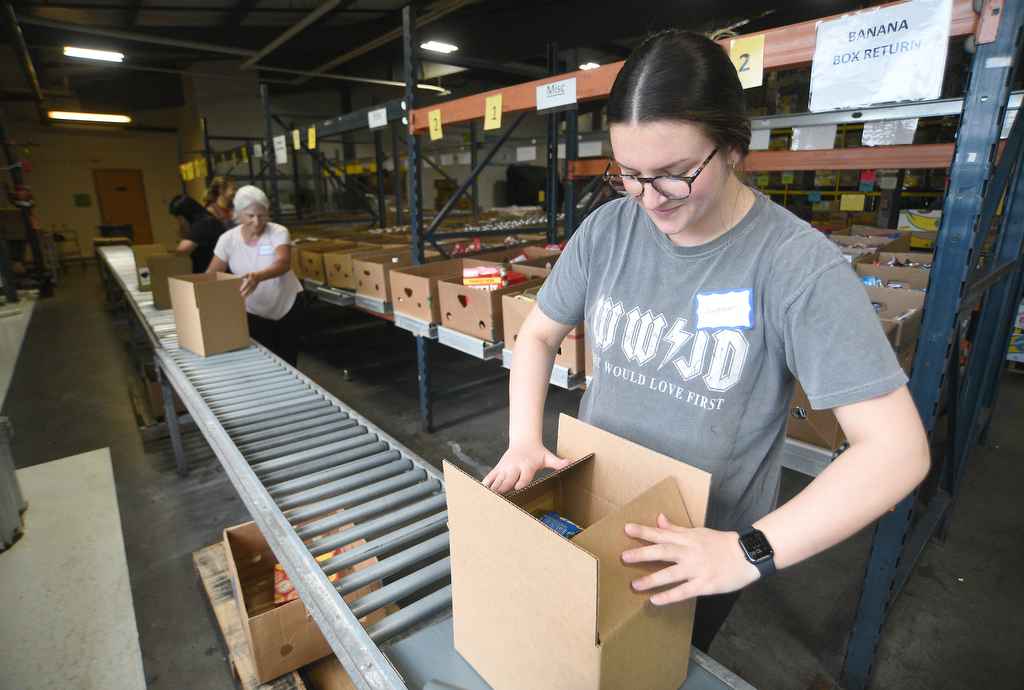 Staff photo by Matt Hamilton/ Volunteer Savannah Boyle packs food into a box for distribution at the Chattanooga Area Food Bank on Friday, April 4, 2025.