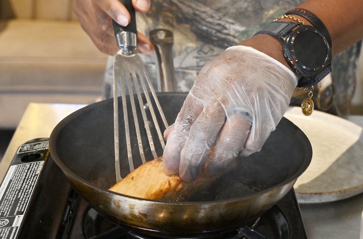 Staff photo by Abby White / Party Bites chef Antonio Tate blackens a seasoned salmon fillet.