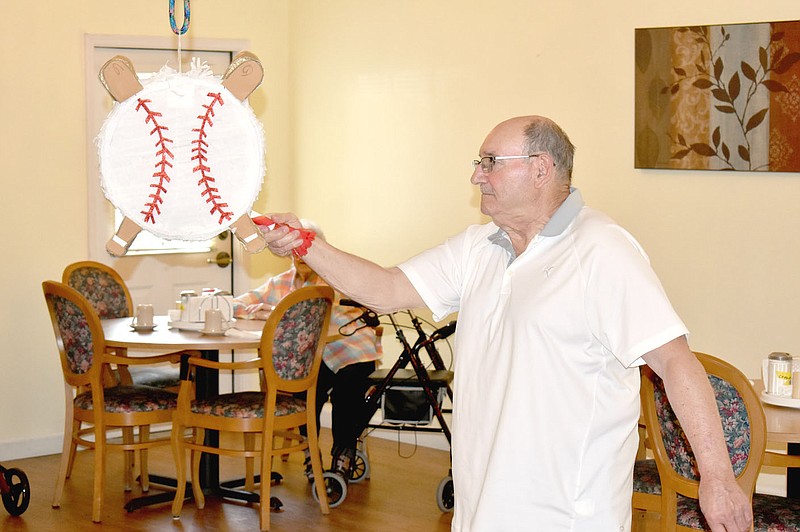 MARK HUMPHREY  ENTERPRISE-LEADER/Carroll Ray "C.R." Bell, puts a miniature bat to a baseball piñata during a reception held in his honor at Farmington's Peachtree Village Friday afternoon. Bell was inducted into the Arkansas Softball Hall of Fame on July 2 at North Little Rock.
