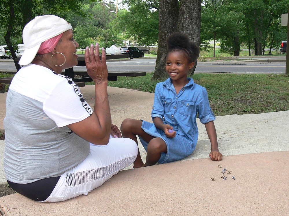 Tina Willis (left) of Hot Springs congratulates her granddaughter Syncere for being quick to learn to play jacks at Hollywood Park in Hot Springs. (Special to the Democrat-Gazette/Jerry Butler)