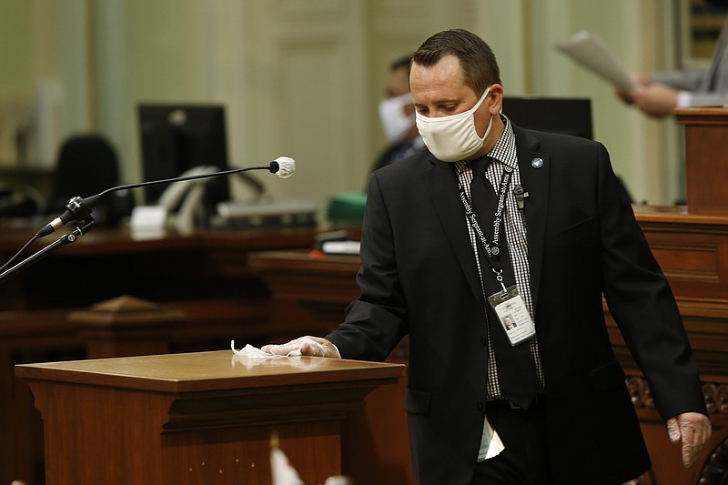 Assembly Sgt.-at-Arms Larry Williams disinfects the podium after its use by an Assembly member at the Capitol in Sacramento, Calif., Monday, June 8, 2020. The Assembly held its first full session, Monday, since going into a recess in March due to the coronavirus pandemic. (AP Photo/Rich Pedroncelli)