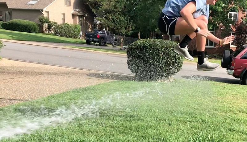 Meredith Pinkston leaps the stream of water while doing the Sprinkler Race. (Arkansas Democrat-Gazette/Celia Storey)