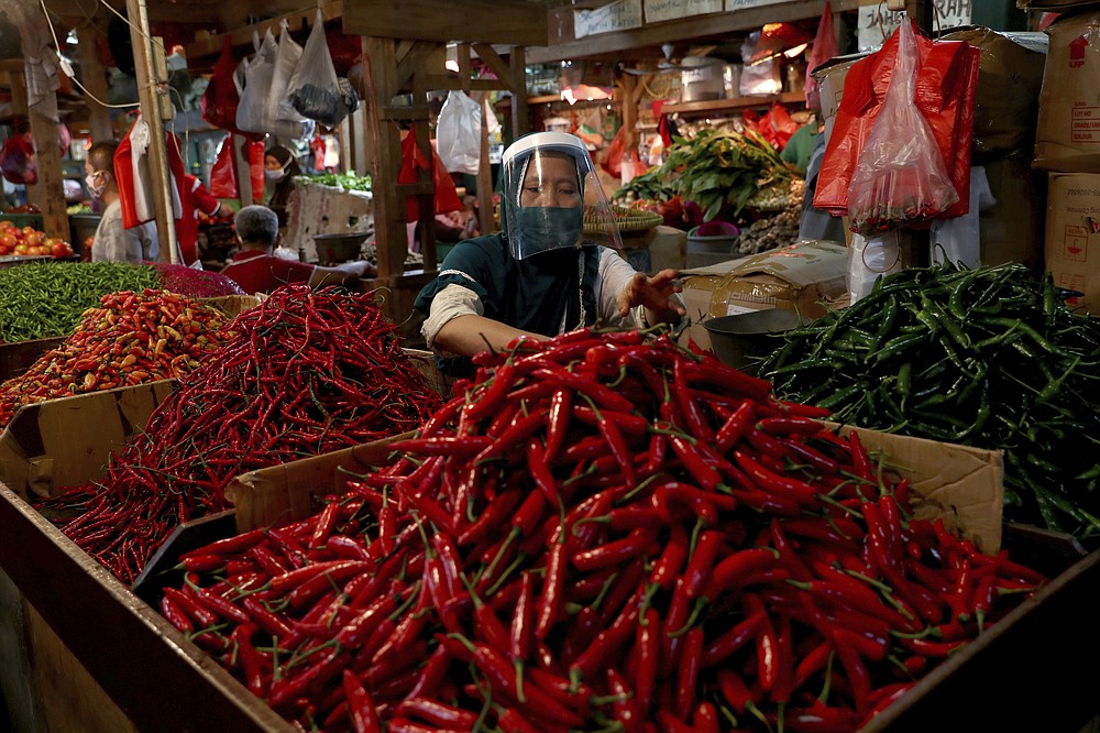FILE - In this June 2, 2020, file photo, a chili pepper vendor wears a face mask and shield as a precaution against the new coronavirus at a traditional market in Jakarta, Indonesia. As Indonesia’s overall virus caseload continues to rise, Jakarta's governor has moved to restore normalcy by lifting some restrictions, saying that the spread of the virus in the city of 11 million has slowed down after peaking in mid-April. This has raised concerns among some, with experts warning that reopening too soon can cause Jakarta to be hit with a second wave of the virus. (AP Photo/Tatan Syuflana, File)