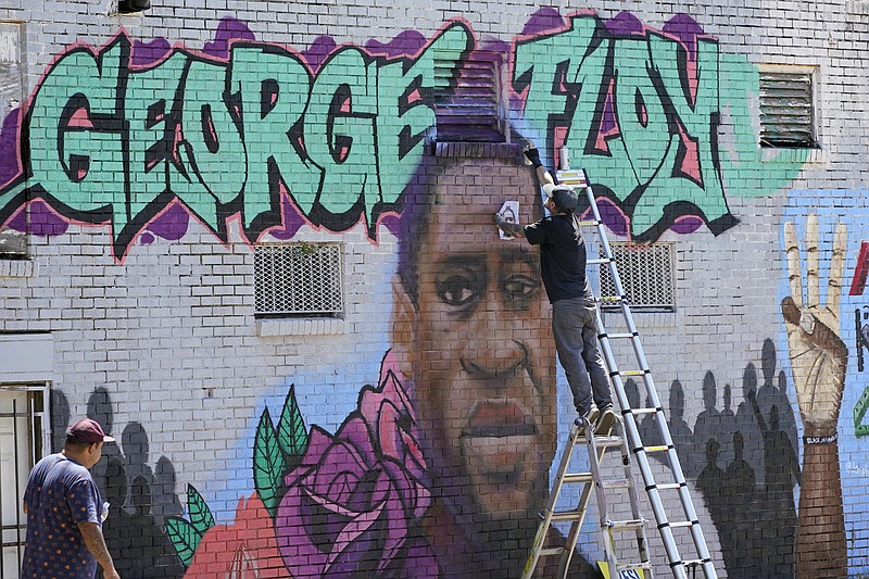 In this Sunday, June 7, 2020, photo, Zack Murray paints a mural honoring George Floyd, on the side of a building in Houston’s Third Ward. Floyd, who grew up in the Third Ward, died after being restrained by Minneapolis police officers on Memorial Day. (AP Photo/David J. Phillip)