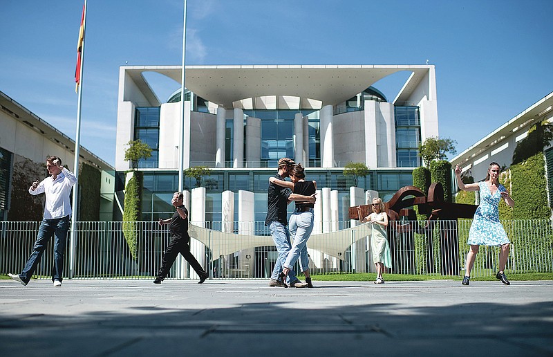 FILE - In this June 3, 2020, file photo, people dance in front of the Chancellery, office of German Chancellor Angela Merkel, in Berlin on the occasion of the action day 'Save the world cultural heritage Tango Argentino in Germany' to point out the problems of tango dancers and dance schools caused by the coronavirus pandemic. Just as summer beckons, Europeans are re-inhabiting their cafes, parks and beaches abandoned during months of lockdown to check the spread of the coronavirus. (Bernd von Jutrczenka/dpa via AP, File) story.lead_photo.caption