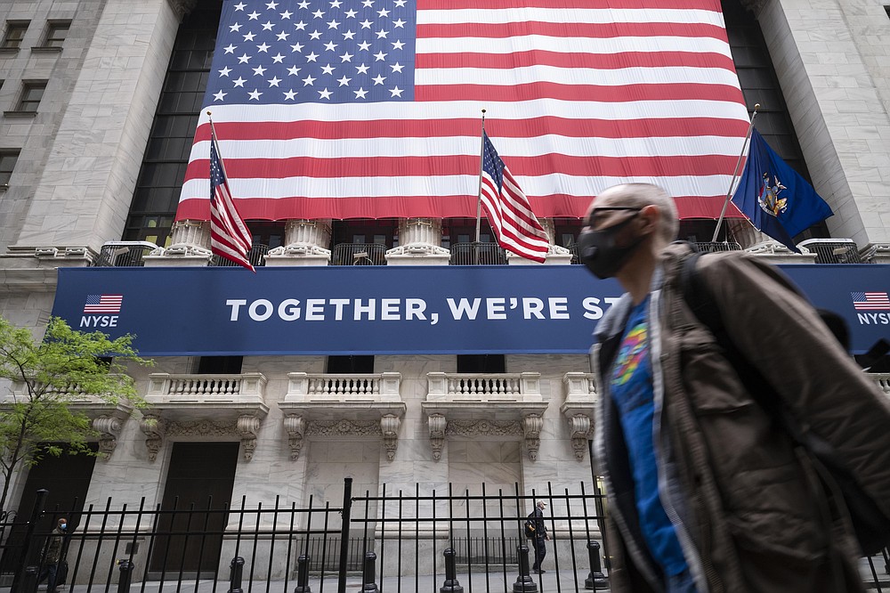FILE - In this May 26, 2020, file photo, a man wearing a protective face mask passes the New York Stock Exchange, as employees arrive for the partial reopening of the trading floor. Stocks fell sharply Thursday, June 11, 2020, on Wall Street as coronavirus cases in the U.S. increased again, deflating recent optimism for a quick economic recovery and raising more doubts about how long the market’s scorching comeback can last. (AP Photo/Mark Lennihan, File)