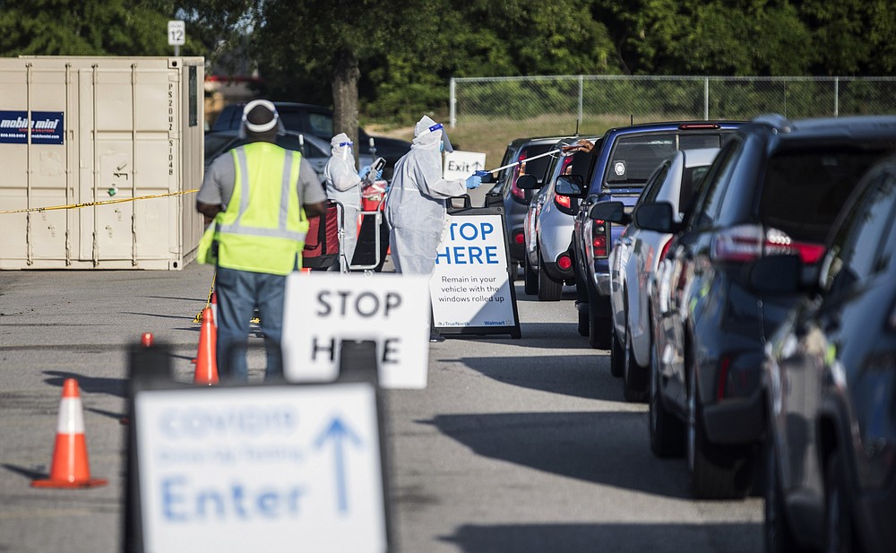 FILE - In this May 15, 2020, file photo, Walmart employees conduct COVID-19 testing for pre-registered individuals in the parking lot of the Ramsey Street Walmart in Fayetteville, N.C. Coronavirus cases are rising in nearly half the U.S. states, as states are rolling back lockdowns. (Julia Wall/The News & Observer via AP, File)
