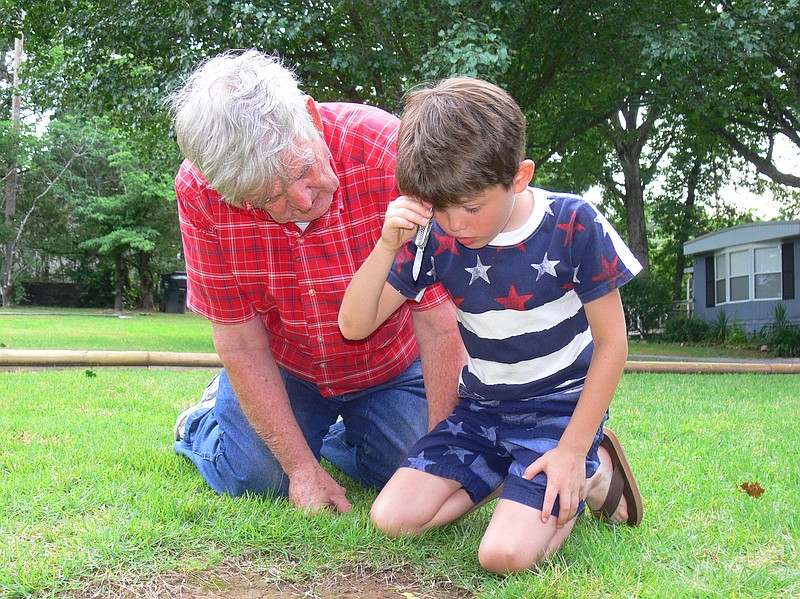 Jerry Butler (left) teaches great-grandson Gavyn White to do a tricky head drop, one of the moves in the old-fashioned game mumbledy-peg. (Special to the Democrat-Gazette/Jerry Butler)