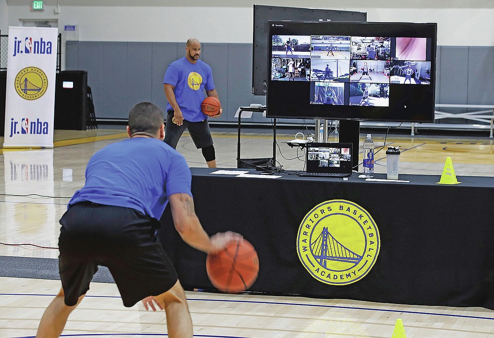 In this photo taken on Tuesday, June 9, 2020, coach Jose Rivera goes through a drill with his virtual students at Golden State Warriors basketball camp in Oakland, Calif. The Warriors had to adapt their popular youth basketball camps and make them virtual given the COVID-19 pandemic. (AP Photo/Ben Margot)