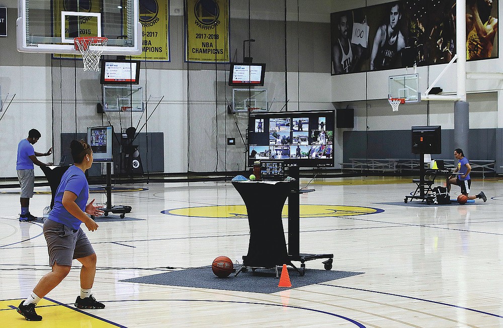 In this photo taken on Tuesday, June 9, 2020, coaches including VeAnne Navarro, left, work with virtual students at Golden State Warriors basketball camp in Oakland, Calif. The Warriors had to adapt their popular youth basketball camps and make them virtual given the COVID-19 pandemic. (AP Photo/Ben Margot)
