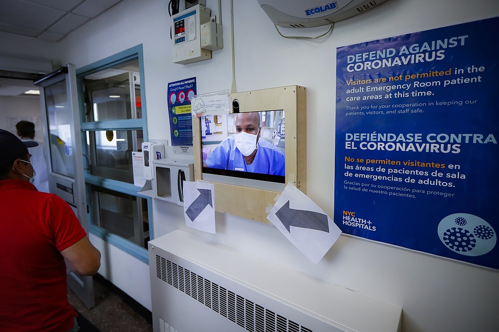 Visitors at the entrance to the emergency department intake area at NYC Health + Hospitals Metropolitan are greeted by a nurse on a video screen Wednesday, May 27, 2020, in New York. At hospitals around the country, nurses, doctors and other health care workers are reckoning with the psychological toll of the virus fight, coupled with fears that the disease could flare anew later this year. (AP Photo/John Minchillo)