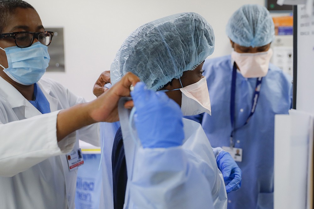 Medical personnel adjust their personal protective equipment while working in the emergency department at NYC Health + Hospitals Metropolitan, Wednesday, May 27, 2020, in New York. At hospitals around the country, nurses, doctors and other health care workers are reckoning with the psychological toll of the virus fight, coupled with fears that the disease could flare anew later this year. (AP Photo/John Minchillo)