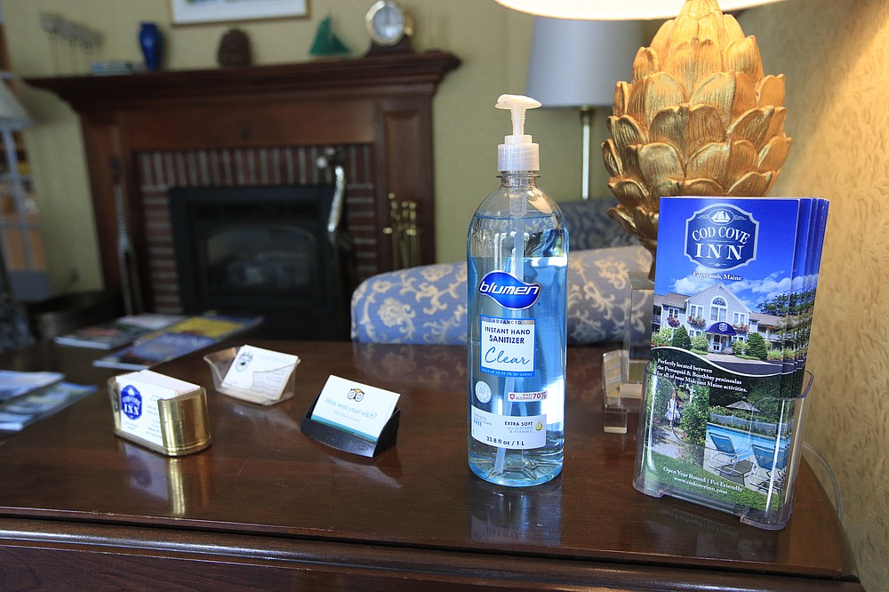 In this Wednesday, June 10, 2020, photo, hand sanitizer is provided for guests in the lobby of the Cod Cove Inn in Edgecomb, Maine. Home-bound travelers desperate to venture out for the first time since the pandemic are confronting a vacation landscape this summer that may require coronavirus tests for the family and even quarantines. (AP Photo/Robert F. Bukaty)