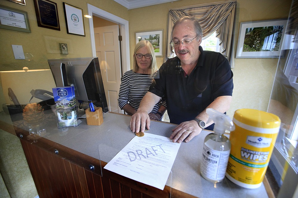 In this Wednesday, June 10, 2020, photo, Cod Cove Inn owners Ted and Jill Hugger show a draft of a compliance form that inn owners may be required to have out-of-state guests sign before being allowed to check in at their inn in Edgecomb, Maine. The form is part of the "Keep Maine Healthy" plan the state is proposing to help prevent the spread of the coronavirus. Residents of New Hampshire and Vermont would be exempt. (AP Photo/Robert F. Bukaty)