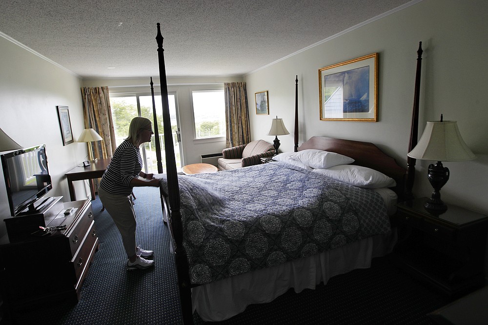 In this Wednesday, June 10, 2020, photo, Cod Cove Inn owner Jill Hugger adjusts a bedspread in a room at her inn in Edgecomb, Maine. During the coronavirus pandemic, inn owners are dealing with working to reopen while the state grapples with how to help prevent the spread of the virus. (AP Photo/Robert F. Bukaty)