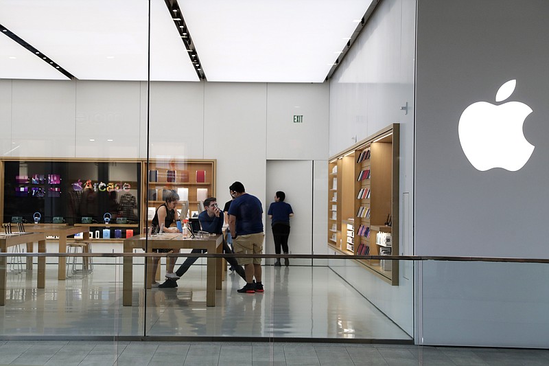 FILE - In this March 14 2020 file photo, Apple employees work inside a closed Apple store in Miami. Apple is temporarily closing 11 stores in Arizona, Florida, North Carolina and South Carolina just few weeks after reopening them in hopes that consumers would be able to shop in them without raising the risk of infecting them or company workers with the novel coronavirus that caused COVID-19.  (AP Photo/Lynne Sladky, File)