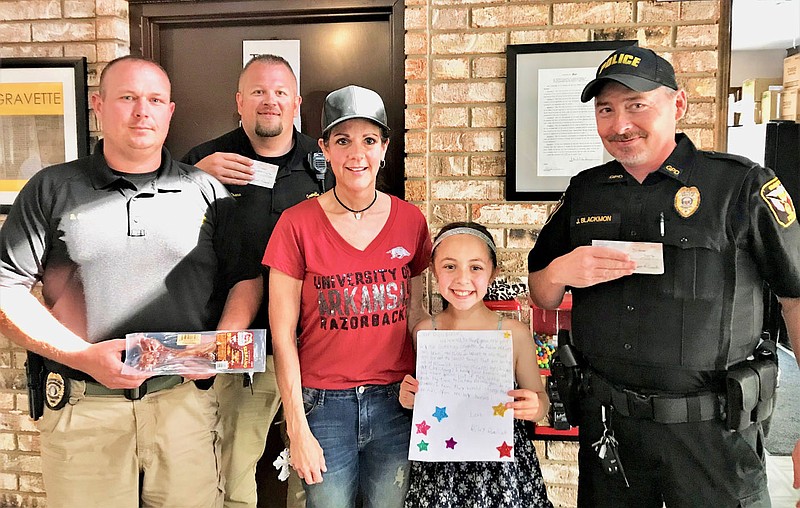 Submitted Photo
Officers from the Gravette Police Department pose with gifts they received from recent visitors Riley and Marian who brought a bone for retired canine officer IKKS and a $1,000 donation toward the purchase of a new canine officer. That puts the department about halfway toward their goal of $15,000 for a new dog. Pictured are Captain Bryan Smith (left), school resource officer Josh Crane, Marian and Riley and Officer Jason Blackmon.