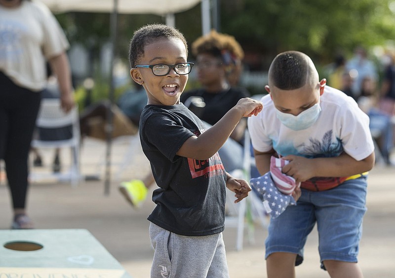 Osafa Hippolyte (left), 3, of Bentonville plays cornhole Friday, June 19, 2020, with Isaiah Palos, 7, of Rogers during a Juneteenth cookout at Lawrence Plaza in Bentonville. Go to nwaonline.com/200620Daily/ to see more photos.
(NWA Democrat-Gazette/Ben Goff)