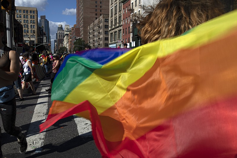 FILE - In this June 30, 2019, file photo parade-goers carrying rainbow flags walk down a street during the LBGTQ Pride march in New York, to celebrate five decades of LGBTQ pride, marking the 50th anniversary of the police raid that sparked the modern-day gay rights movement. Democrats flooded Twitter and email inboxes this week with praise for the watershed Supreme Court decision shielding gay, lesbian and transgender people from job discrimination.  (AP Photo/Wong Maye-E, File)