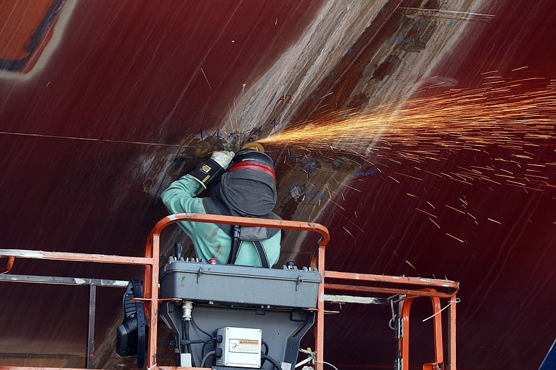 FILE - In this Aug. 29, 2018, file photo, a welder works on the hull of a Zumwalt-class destroyer being built in the shipyard at Bath Iron Works in Bath, Maine. Workers at one of the Navy’s largest shipbuilders overwhelmingly voted to strike, rejecting Bath Iron Works’ three-year contract offer Sunday, June 21, 2020, and threatening to further delay delivery of ships.   (AP Photo/Robert F. Bukaty, File)